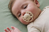 Bébé endormi dans son lit avec une tétine LIYAN crème